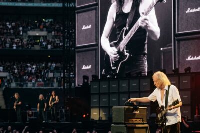 ANGUS YOUNG STOPPED MID-SOLO DURING “BACK IN BLACK,” TOOK OFF HIS SCHOOLBOY CAP, AND PLACED IT ON THE EMPTY AMP WHERE MALCOLM STOOD FOR 41 YEARS… AND 70,000 FANS FELL SILENT. Two brothers from Glasgow built the loudest band on earth. Malcolm played stage right — never flashy, never center — just the thundering rhythm that made AC/DC unstoppable for four decades